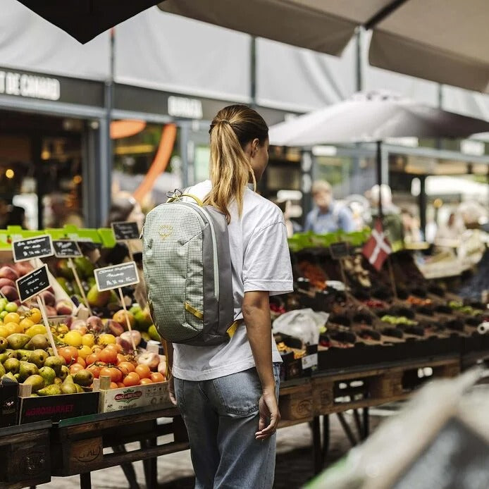 Woman with a backpack shopping at an outdoor market.