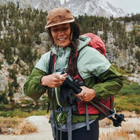 Person hiking in a mountainous area with a backpack and trekking poles.