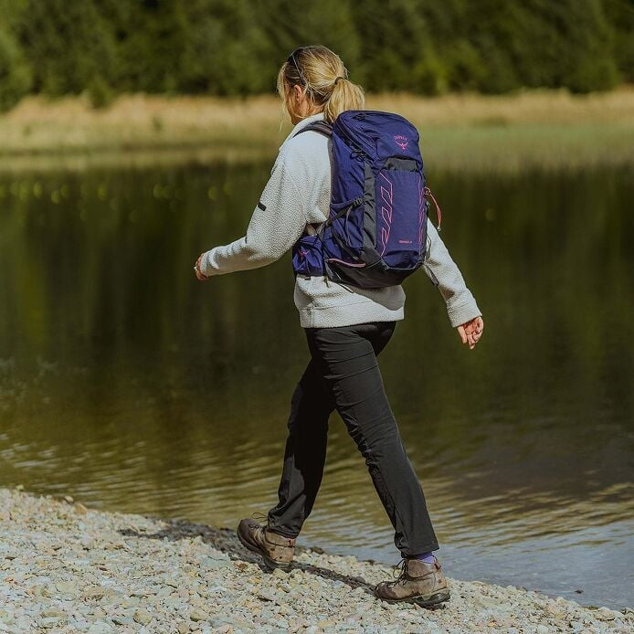 Person with a purple backpack walking along a lakeside path