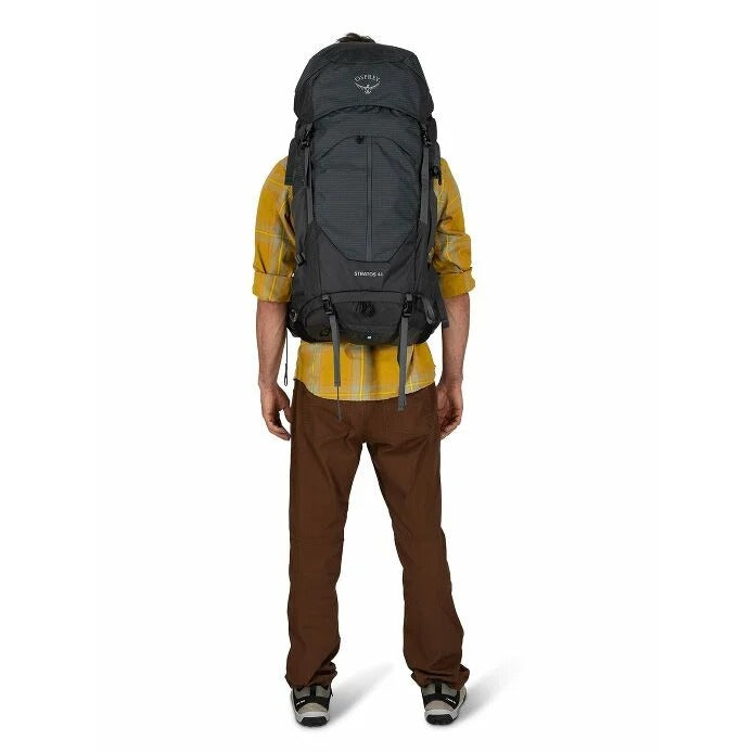 Person wearing a large black backpack on a white background