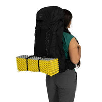 Person carrying a large black backpack with yellow sleeping pad on a white background