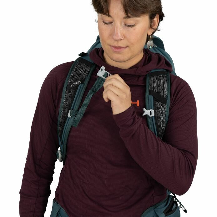 Teal hiking backpack close-up of chest strap clip being adjusted by hand