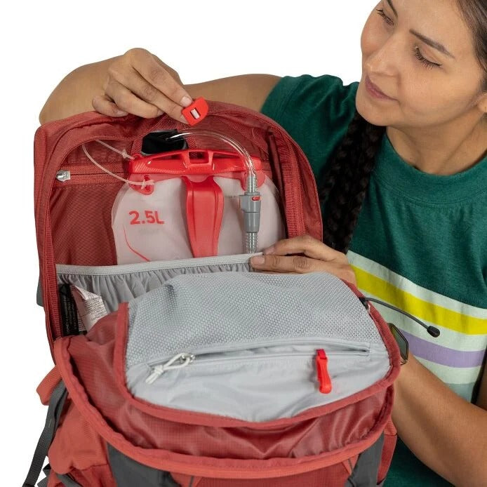 Person opening a red backpack with a water filter inside, on a white background