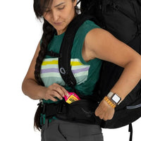 Woman with a backpack using a measuring tape on a white background