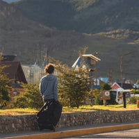 Person sitting on a curb with mountains and buildings in the background