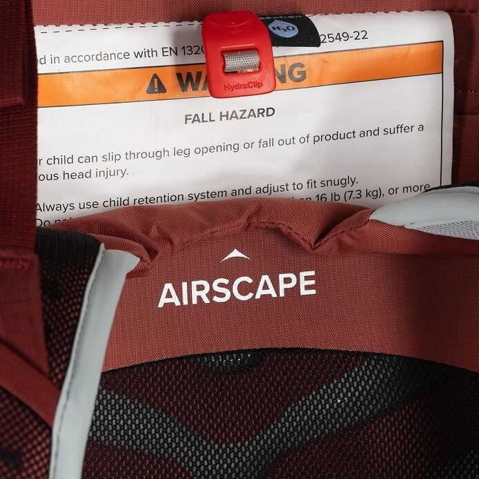Red child safety seat with 'AIRSCAPE' branding and warning label.