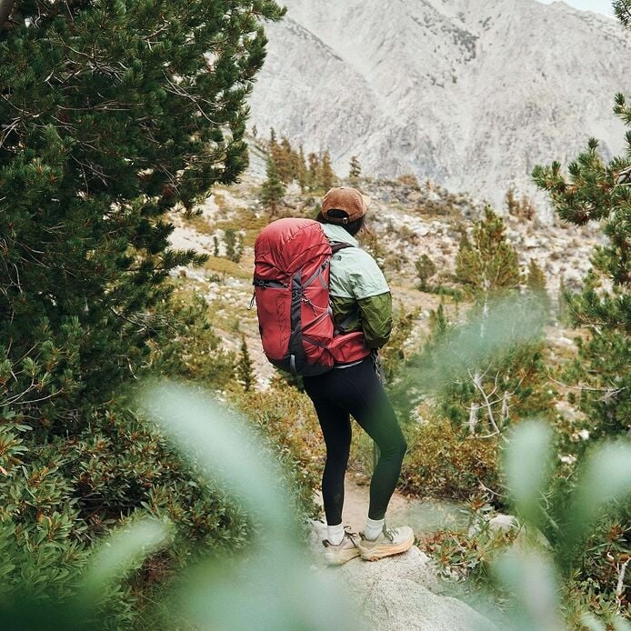 Person hiking in a mountainous area with a red backpack