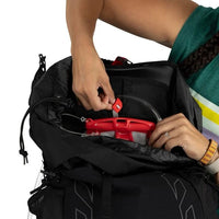 Person packing a red object into a black backpack on a white background