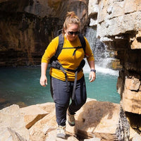 Person hiking near a waterfall with a backpack