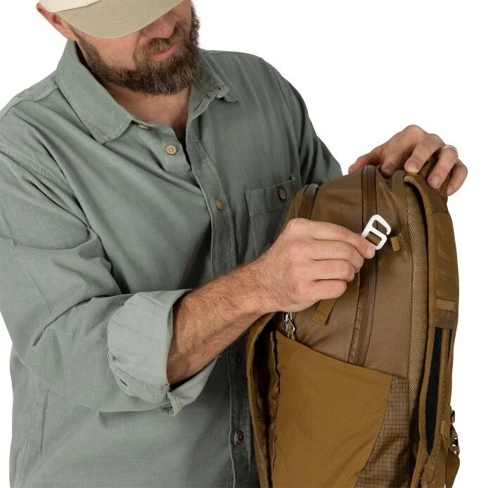 Man adjusting a brown backpack with a white buckle on a white background