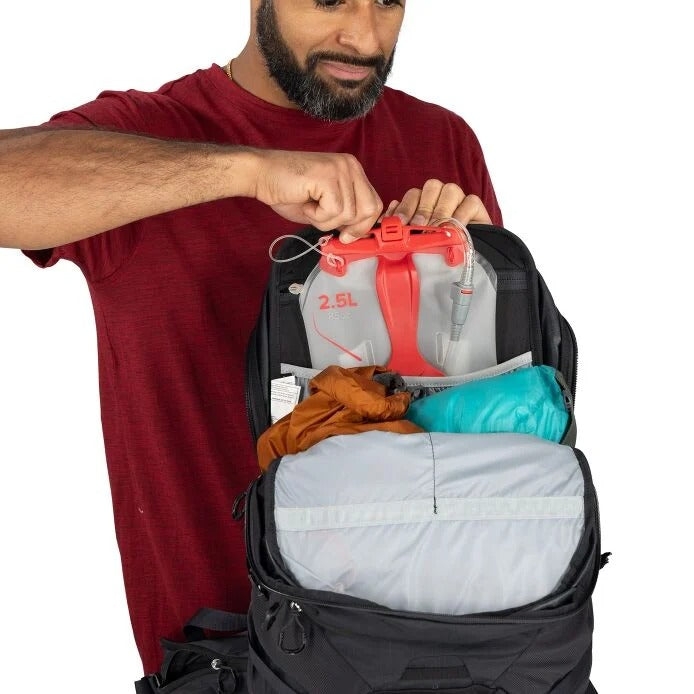 Black hiking backpack opened to show internal compartments and a 2.5L hydration bag