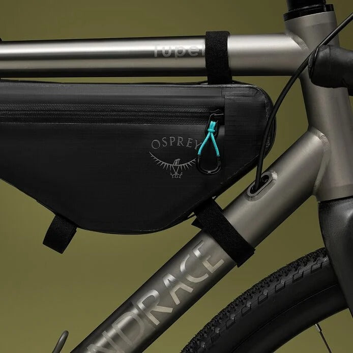 Bicycle frame with a black Osprey bikepacking bag on a green background