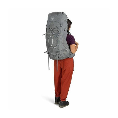 Person wearing a large gray backpack on a white background
