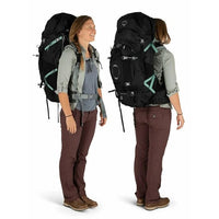 Person wearing a large black backpack with green accents on a white background