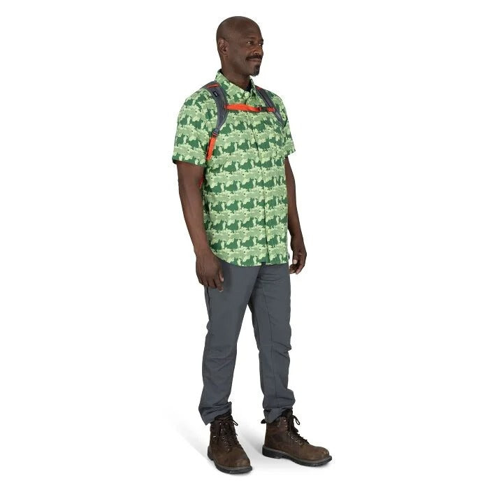 Man wearing a green patterned shirt and gray pants on a white background
