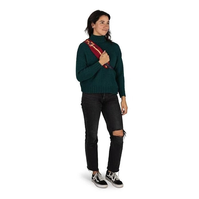 Woman wearing a green sweater and black jeans on a white background