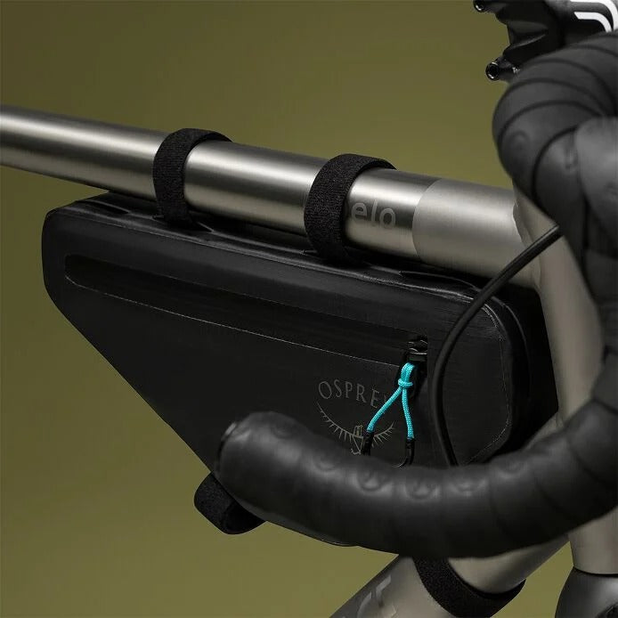 Bicycle handlebar with a black Osprey bag attached on a green background