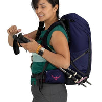 Woman with a backpack holding climbing gear on a white background