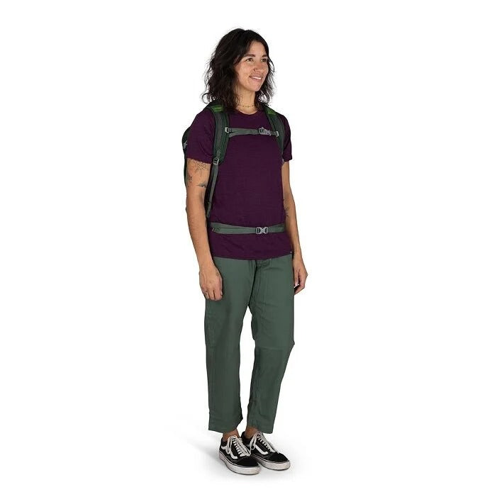 Person wearing a purple shirt and green pants with a backpack on a white background