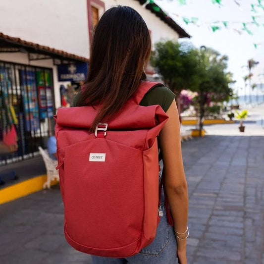 Person wearing a red backpack with a blurred street scene in the background