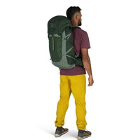 Person wearing a large green backpack on a white background