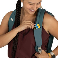 Woman adjusting a backpack strap with a visible brand logo on a white background