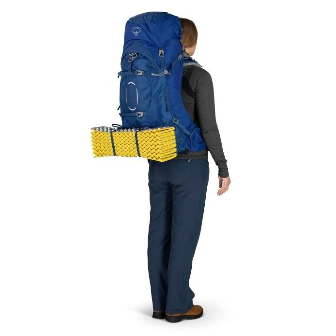 Person wearing a large blue backpack with yellow packs on a white background