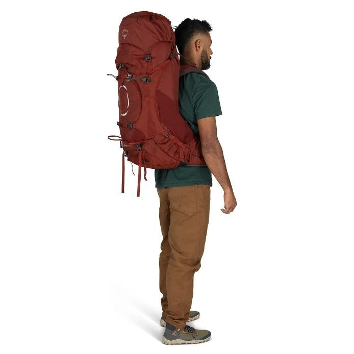 Man wearing a large red backpack on a white background