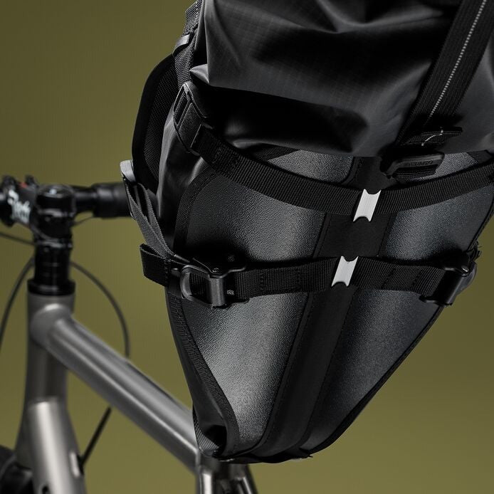 Black bicycle saddle bag attached to a bike frame against a green background