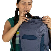 Woman opening a Osprey backpack against a white background