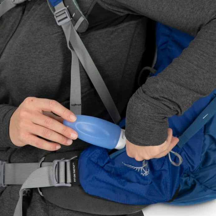 Person adjusting a blue bottle in a child car seat with gray straps.