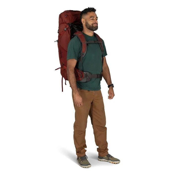Man wearing a large red backpack on a white background