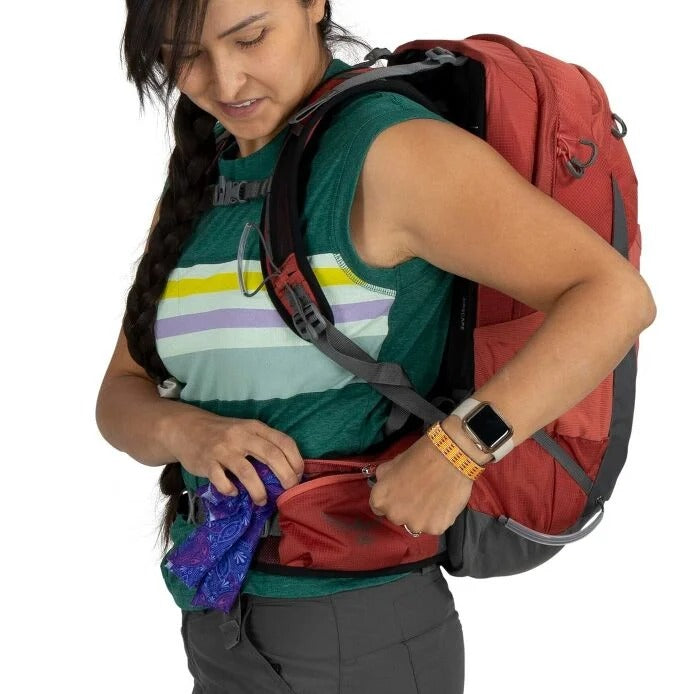 Person with a red backpack adjusting something inside on a white background