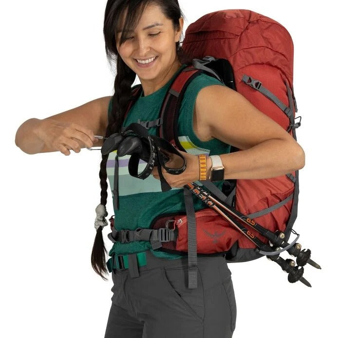 Person wearing a red backpack with climbing equipment on a white background