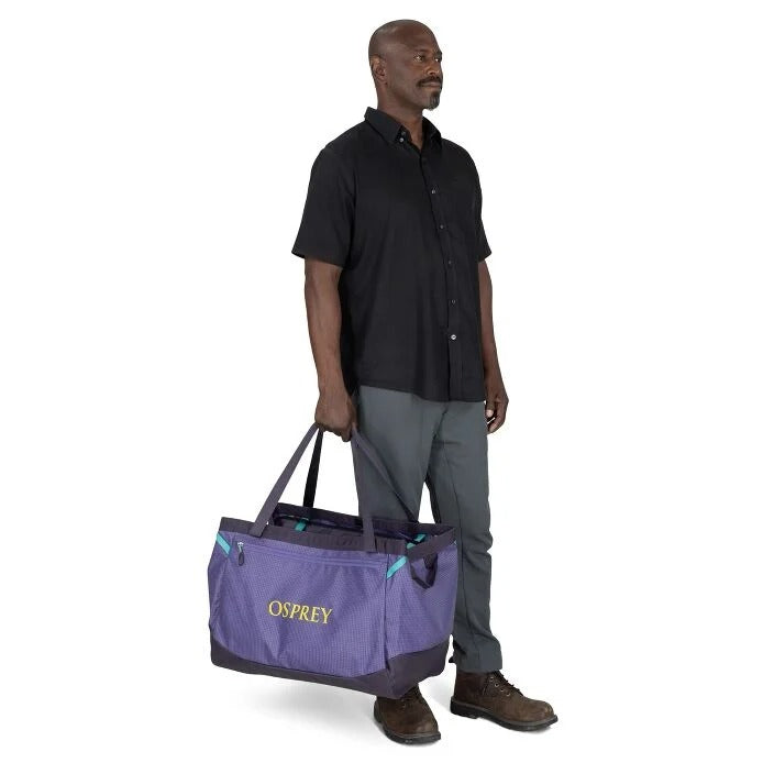 Man holding a purple Osprey bag on a white background